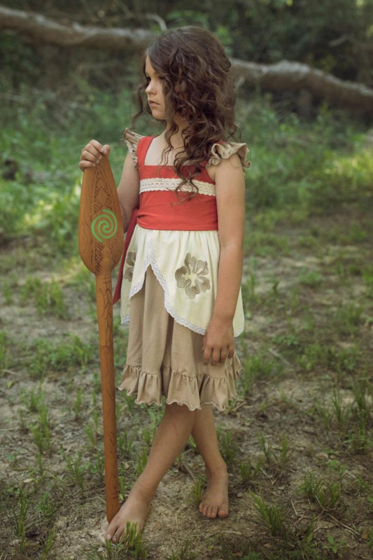 A young girl is wearing the Polynesian Princess Twirl Dress, which features beige and cream fabric accented by a red waistband and decorative floral embroidery.  There is a lace accent on the chest and ruffles on the top of the straps.  There is a ruffle on the hem and a tie on the side of the dress. Perfect for an adventurous princess. 